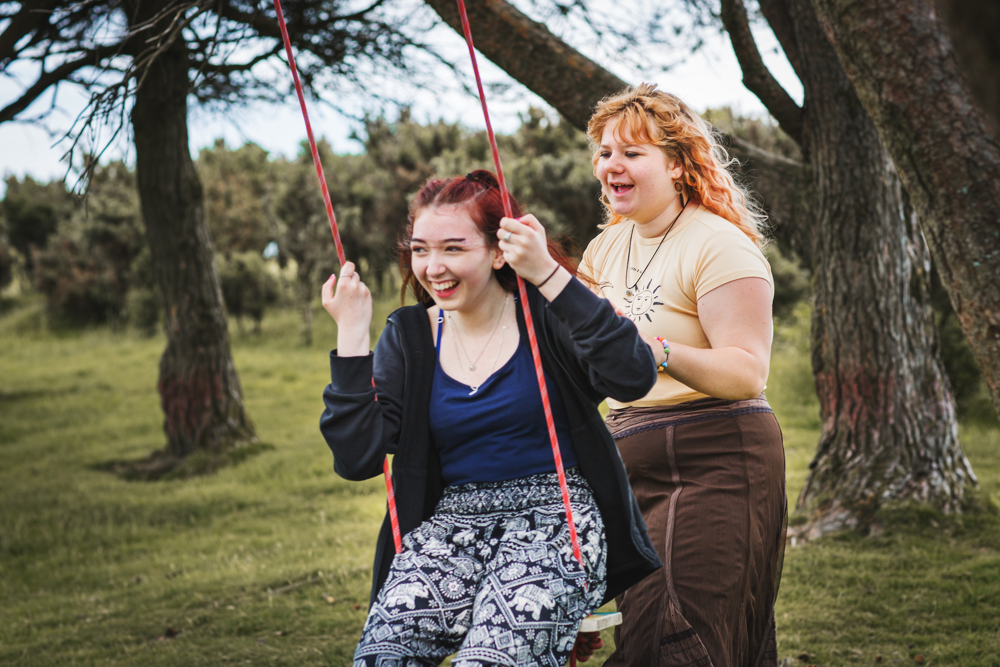Two teenagers playing on swing together in Swansea