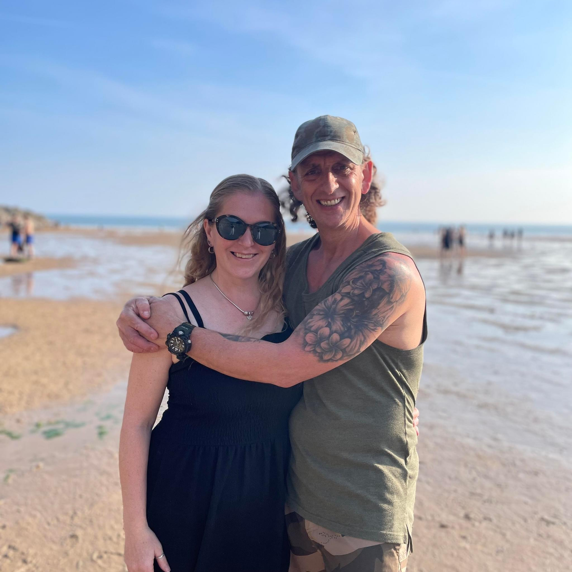 foster carers hugging on a beach